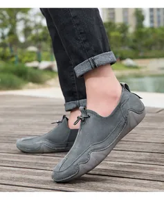 Mocasines gris oscuro en madera mostrando textura de gamuza y suelas antideslizantes