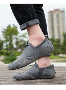 Detalle de mocasines gris oscuro transpirables con suela de goma sobre cubierta madera