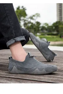 Primer plano de mocasines de ante gris con suelas de goma antideslizantes en madera