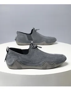 Detalle de mocasín de ante gris con costuras blancas a mano y cordones elásticos