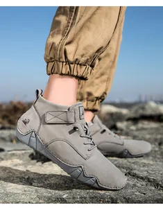 Outdoor-Herrenmodell mit hohen grauen Wildleder-Wanderschuhen mit Riemen und Schnürung