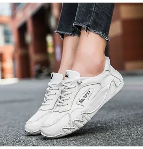 On-foot view of white leather low-top sneakers featuring wavy stitching and DBECI detail