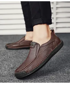 Close-up of brown leather slip-on shoe showing manual stitching and thick rubber sole