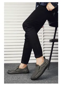 Detail of dark grey leather loafers featuring white hand-stitched seams and brown accents