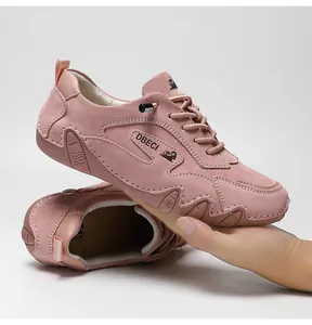 Detail of pink suede sneakers with DBECI logo and brown rubber sole on a white background