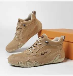 Detail view of khaki suede leather boots featuring orange branding box and stitching