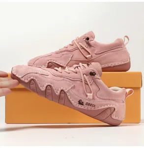 Detailed view of hand-stitched pink suede loafers showing goat logo and non-slip rubber sole