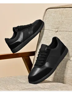 Détails des baskets type German Trainer tout noir en cuir et daim sur un fauteuil