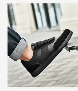 Gros plan de baskets en cuir noir portées avec un jean en denim bleu à revers élégant