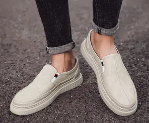 Detail of beige slip-on loafers with lychee texture and tricolor strap on the heel