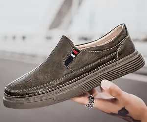Detail of dark brown leather slip-on shoe with white stitching and tri-color ribbon trim