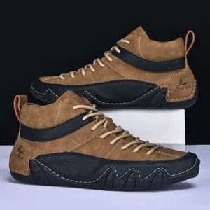 Detail of men's brown mid-top leather boots with wavy non-slip sole and stitching