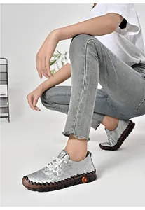 Detailed close-up of floral embossed silver leather casual shoes with thick rubber soles
