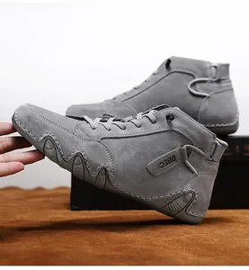Detail showing hand testing soft suede material of high-top grey leather athletic boots