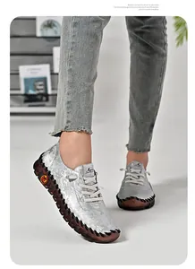 Detail of silver loafers featuring floral texture and non-slip rubber sole with jeans