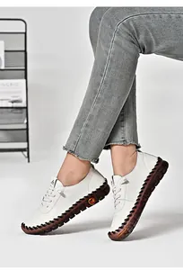 Close-up of white leather casual loafers featuring thick rubber soles and hand-stitched detail