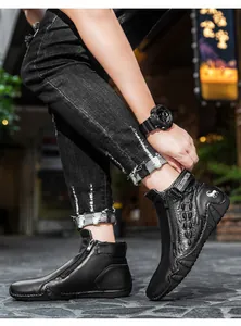 Close-up of black leather boots featuring crocodile texture, side zipper and metal logo