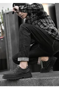 Close-up of black leather work boots with thick rubber soles and metallic lace eyelets