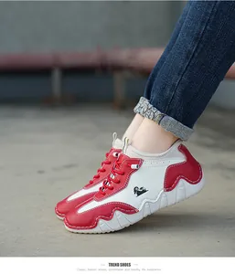 Detail shot of white and red casual sneakers with thick wavy sole on a model outdoors