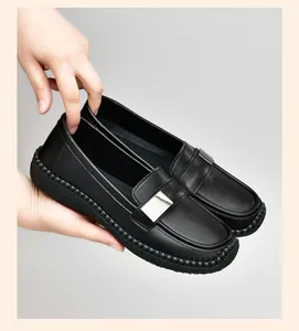 Detalle de mocasines de cuero negro para mujer con una hebilla rectangular de metal plateado