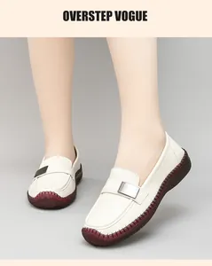 Primer plano de mocasines de cuero beige con hebilla metálica y suela de goma roja