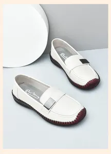 Primer plano del mocasín de cuero blanco con hebilla de metal plateado y suela de goma roja