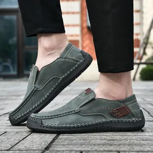 Detail of dark green suede loafers with yellow contrast stitching and rubber soles