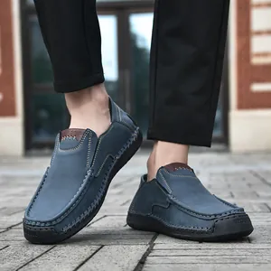 Detail of gray-blue suede loafers featuring handcrafted stitching and thick rubber soles