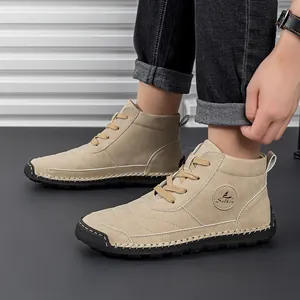 Detail of khaki suede lace-up boots showing logo and durable rubber sole texture