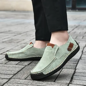 Men's mint green suede loafers with contrast stitching and rubber sole on urban street