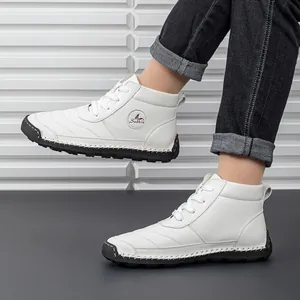 Detail view of white lace-up work boots with stitched rubber soles and side logo