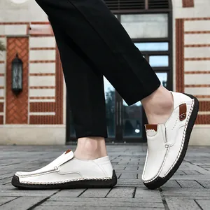 On-foot view of white leather loafers with hand-stitched detailing and metal rivets