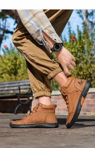 Close-up of brown PU leather boots showing artisanal stitching and non-slip rubber soles