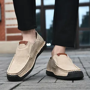 Close-up of khaki suede loafers featuring distinctive white hand-stitched seam details