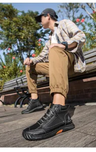 Close-up of black PU leather ankle boots featuring orange vent details and grey woven laces