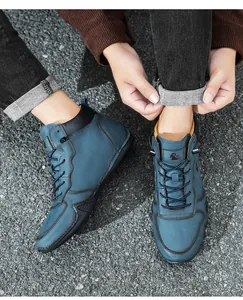 Détail de bottines pour hommes en daim bleu avec coutures fines et logo de chèvre sur la langue