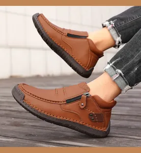 Detalle de botas de cuero marrón con cremallera, remaches y costuras hechas a mano