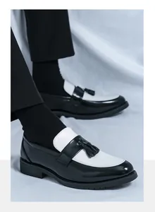 Détail de mocassins pour hommes avec cuir contrasté noir et blanc et pompons élégants