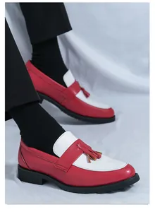 Gros plan sur des mocassins en cuir bicolores rouge et blanc avec franges et semelles noires