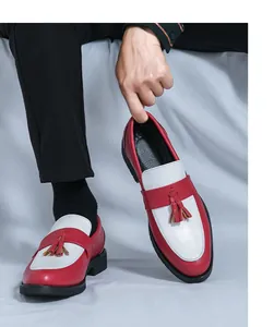 Détail de mocassins en cuir bicolore rouge et blanc avec glands et semelles noires