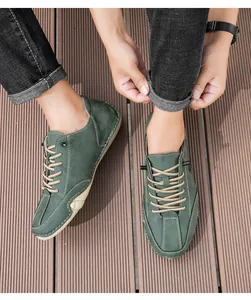 Top-down view of men's dark green suede casual shoes with contrast stitching on wooden floor