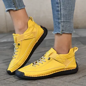 Nahaufnahme gelber Outdoor-Lederschuhe mit dicker schwarzer Gummisohle und Handnaht-Details