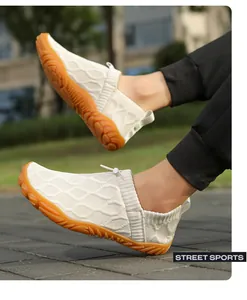 Outdoor close-up of breathable beige knit barefoot shoes with non-slip orange rubber soles