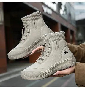Dettaglio stivali in pelle taupe con logo capra, colletto in maglia e suola antiscivolo