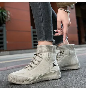 Dettaglio di stivaletti alti in pelle beige con polsino in maglia e lacci su modella