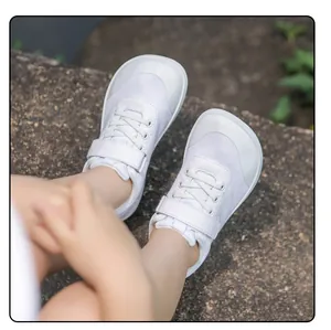 Close-up of kids' white wide-toe barefoot sneakers with breathable mesh and velcro straps