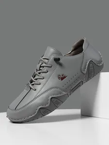 Detalle de zapatos casuales de cuero gris con costuras y logotipo de carnero lateral