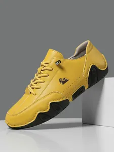 Detalle de zapato casual de cuero amarillo con logo de oveja y suela de goma deportiva