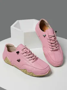 Primer plano de zapato de cuero rosa con suela de goma ondulada y detalle de logo de carnero