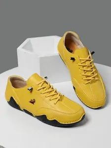 Detalle de zapatos casuales de cuero amarillo con logo de oveja y suela de goma antideslizante